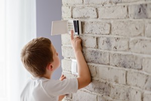 Little baby boy pushes a buttons on the alarm keypad