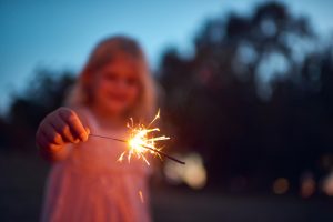 Una foto de una niña irreconocible jugando con una bengala por la noche afuera en la naturaleza