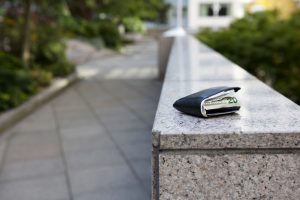 Wallet with cash inside sitting on a stone hand rail