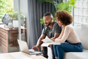 Loving couple paying bills online at home using a laptop computer and looking very happy - lifestyle concepts