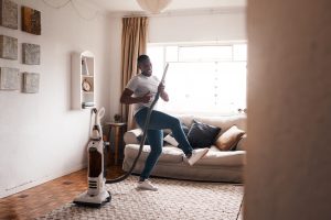 Shot of a young man dancing while busy vacuuming the living room