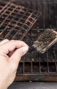Person's hand showing loose bristle from wire grill cleaning brush. Dangerous when it sticks to meat or other food and a person accidentally swallows it. Digestion damage, life threatening situation.