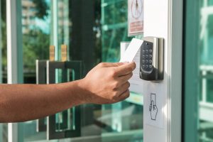Mano usando el escaneo de la tarjeta de llave de seguridad para abrir la puerta para ingresar al edificio privado.  Sistema de seguridad para viviendas y edificios.