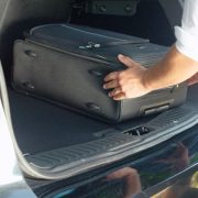 Person putting travel bags in a car trunk