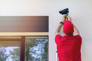 Professional technician installing home security camera, related to the topic of professional vs DIY security camera installation