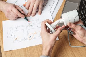 Two people discussing a business security CCTV project. Video security equipment and blueprint on a table.