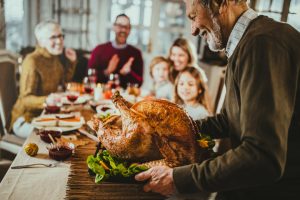 Thanksgiving dinner being served to happy family, a safe and healthy Thanksgiving scene to remind people of Thanksgiving cooking safety tips