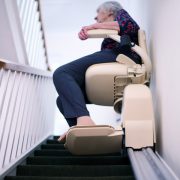 Senior woman sitting on stair lift at home, part of an age-in-place setup